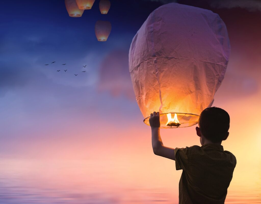 Junge hält einen Wunschballon hoch als Symbol fürs Neue Jahr